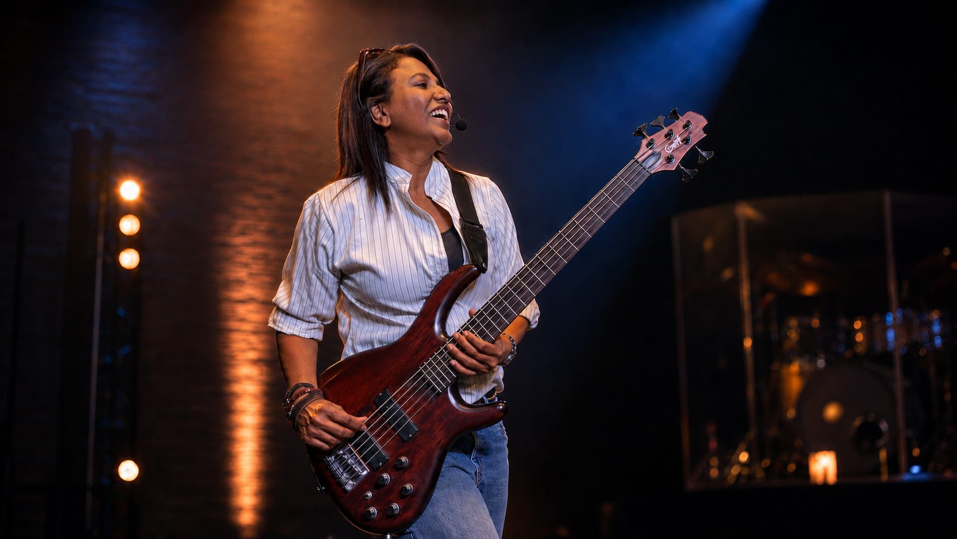 Jazz James smiling on stage while holding a bass guitar.